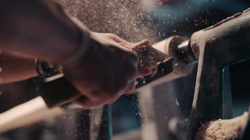 A man is using tools and a machine to carve wood