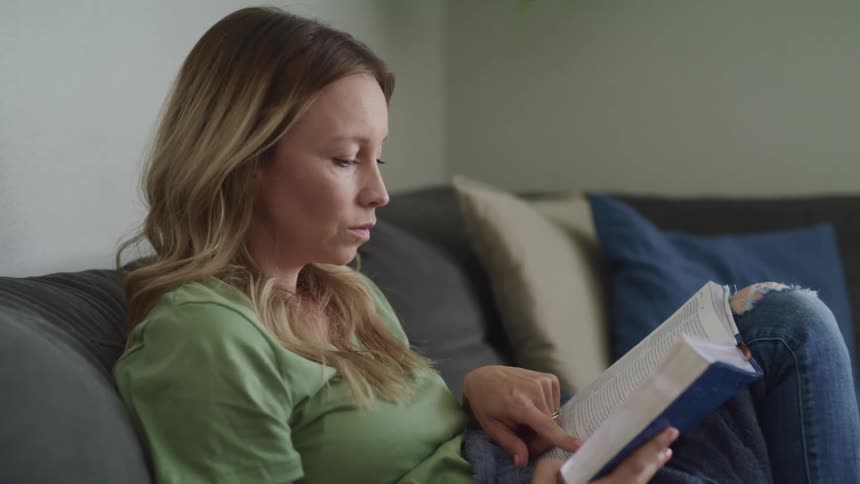 A woman is reading a book indoors