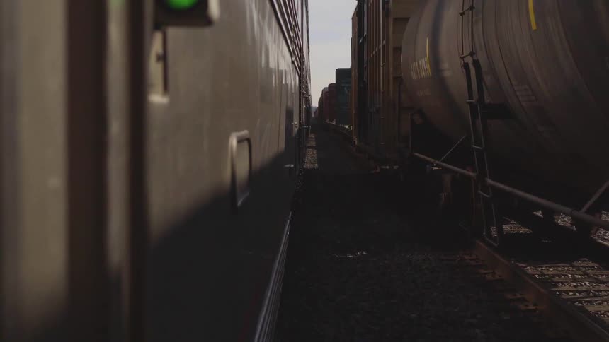 Two cargo trains closely passing each other on the tracks