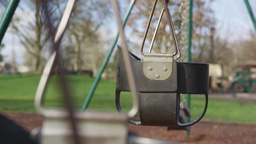 A playground with a swing set surrounded by grass and trees