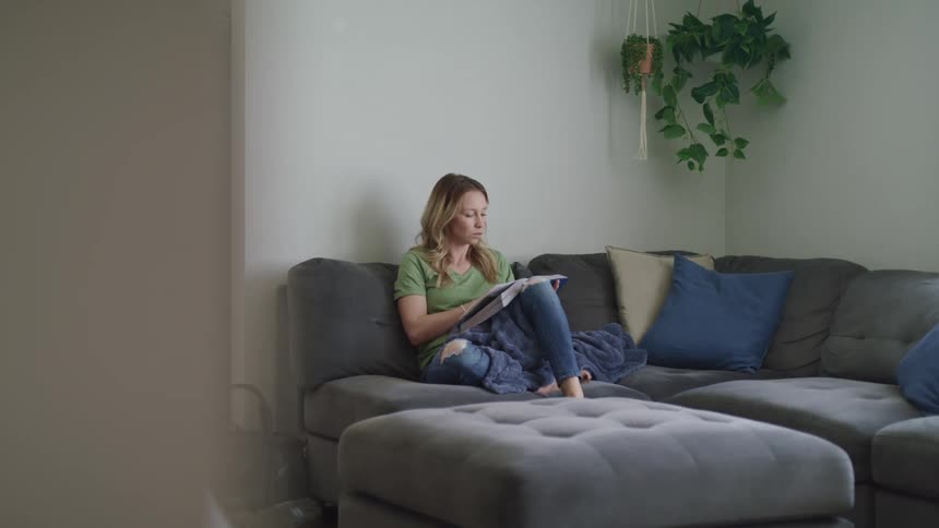 Woman sitting on couch reading a book