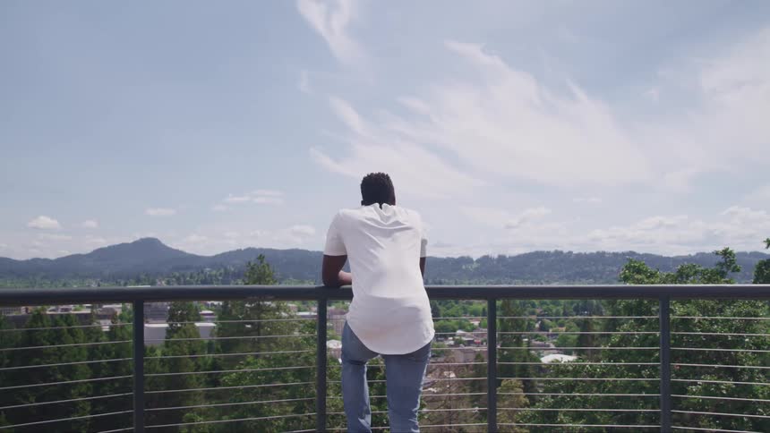 A man is leaning against the railing taking in the view
