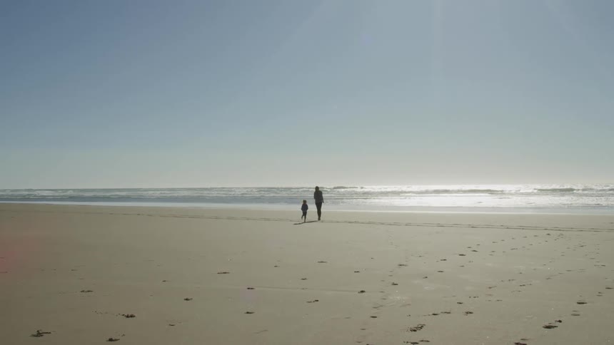 Mother and daughter playfully walking on the sands of a beach at day time