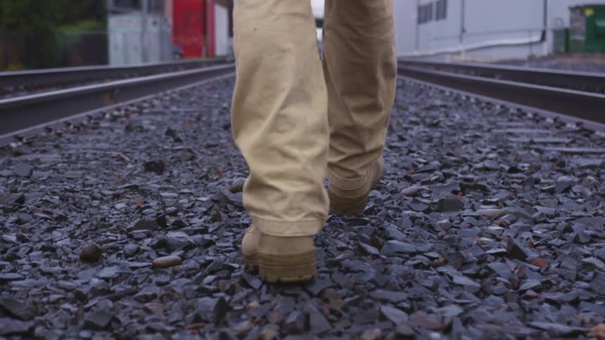 A man walking down the middle of train tracks