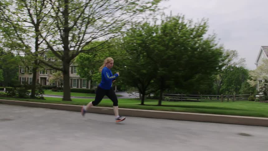 A woman jogs in a neighborhood during the daytime