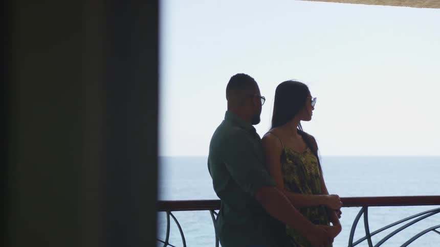 A reveal of two people standing on the edge of a beach