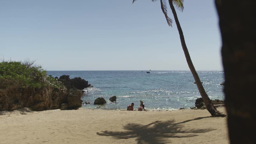 Two people sit on the beach enjoying the ocean