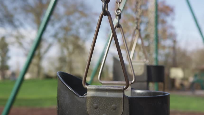Children swings on a playground in a park at day time