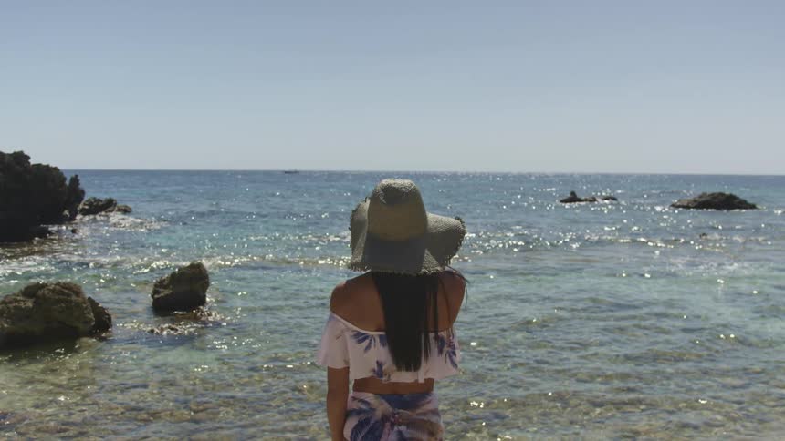 A woman standing on the beach look at the water