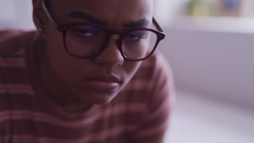 A woman in a room with glasses and earrings looking up and staring