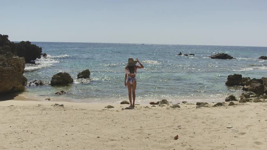 A woman standing on the edge of a beach