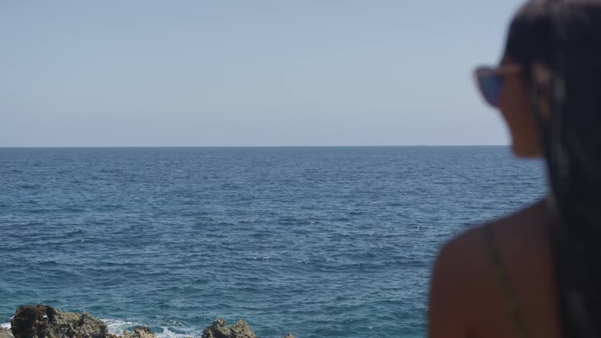 Woman wearing sun glasses looking out at the ocean at daytime