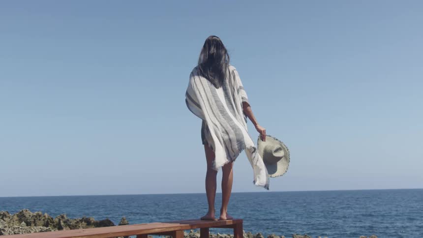 A woman stands by the water on a windy day