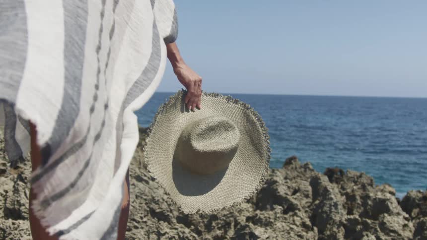 A woman standing on the rocky shore