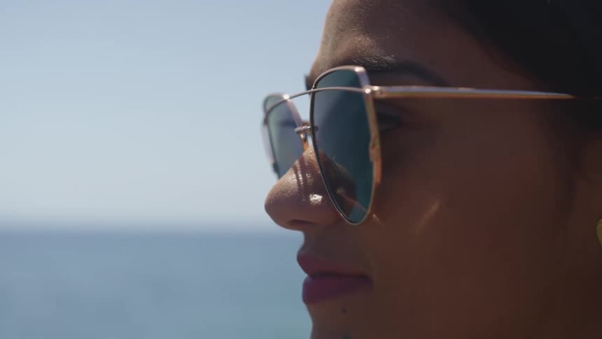 Woman wearing rose gold rimmed sunglasses staring off into the distance