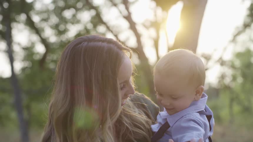 A woman is holding a male infant while smiling