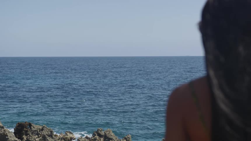 Woman sitting on the coast watching the ocean