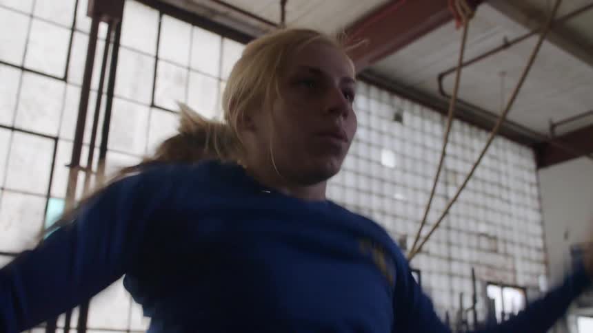 A woman does jumping jacks in the gym