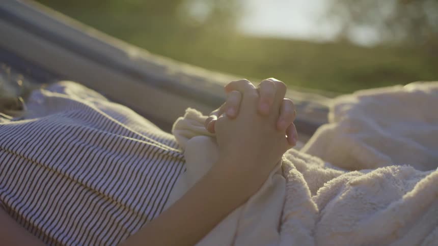 Young girl resting on a hammock in the backyard at sunset