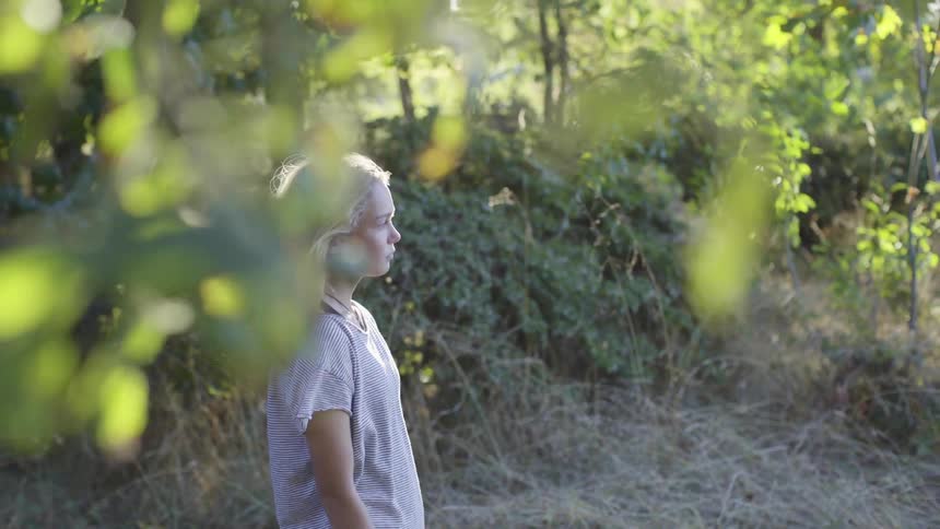 Blonde girl standing on the forest looking at the horizon at morning