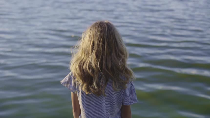 A girl looks out over a body of water on a sunny day
