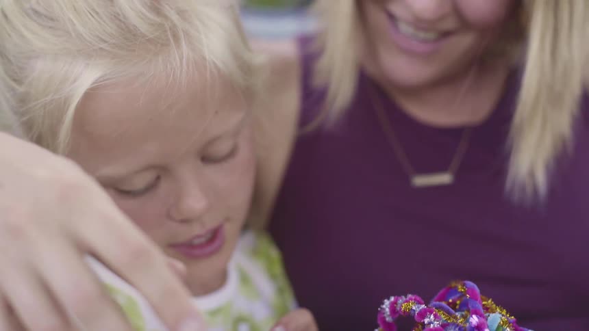 A woman sits next to a young girl who holds an object in her hands
