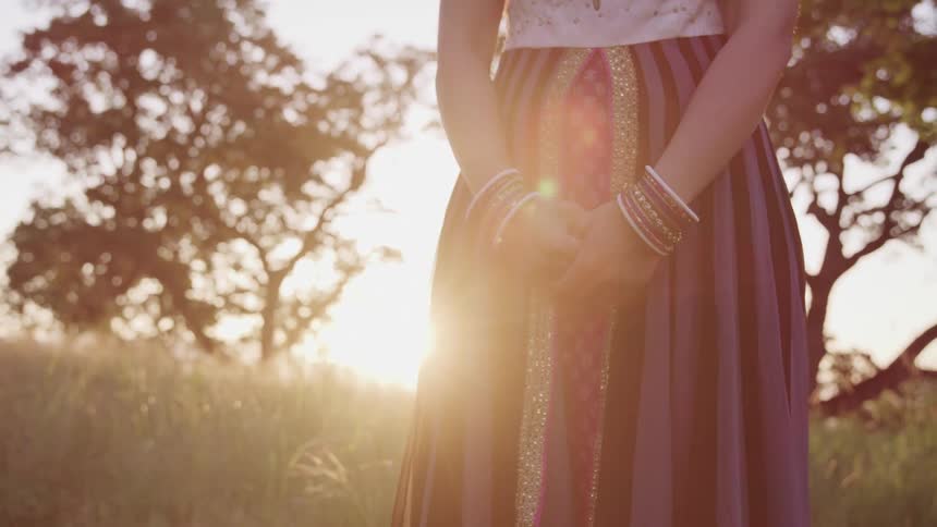 A woman is standing outdoors at dusk