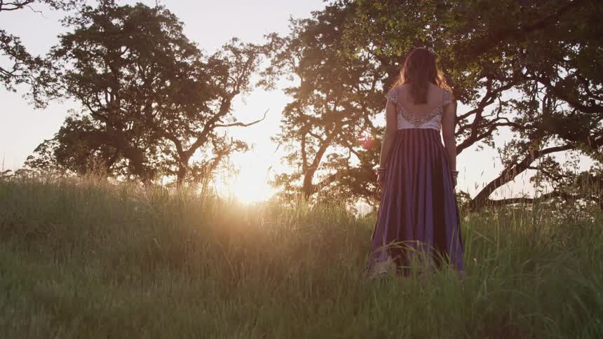 A woman is walking in a meadow at dusk