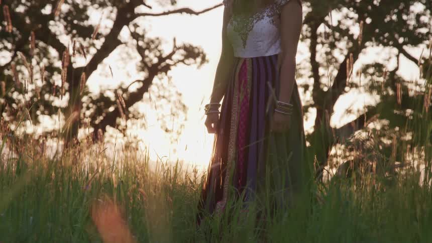 Woman stands in field with sun shining from red sky