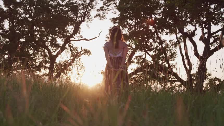 A woman is standing outdoors at dusk