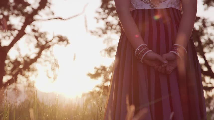 An indian woman standing in front of a sunset