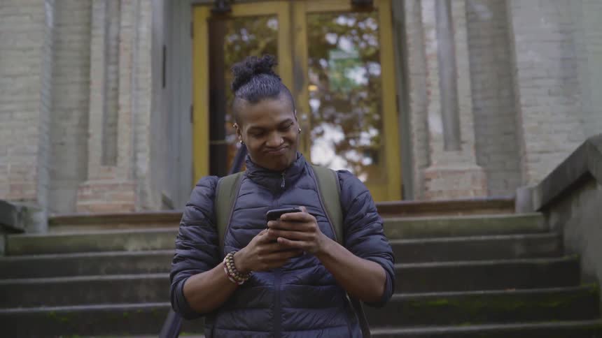 A man taking a selfie with cell phone in front of steps of a building