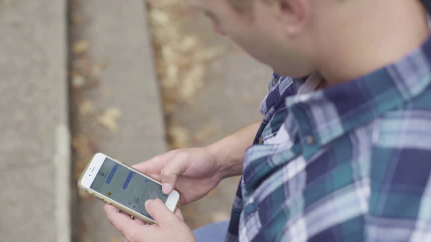 Man standing on the steps of a stair texting on a smartphone outdoors