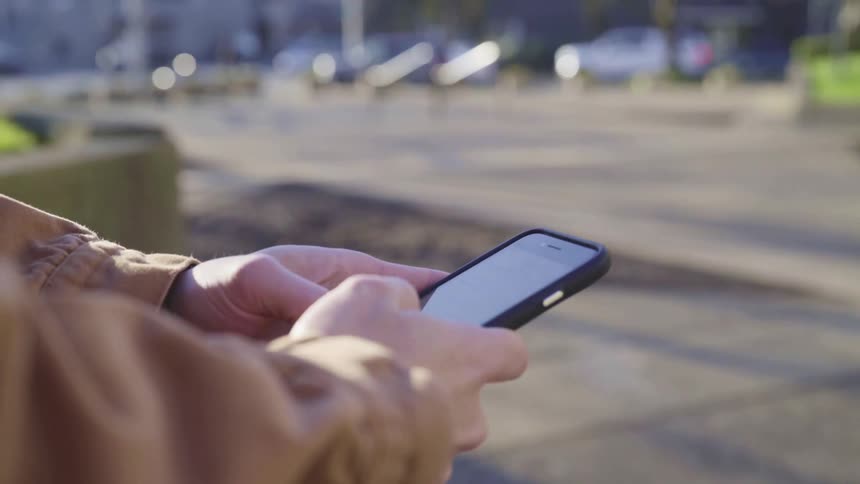 Man texting on a smartphone in the city at morning