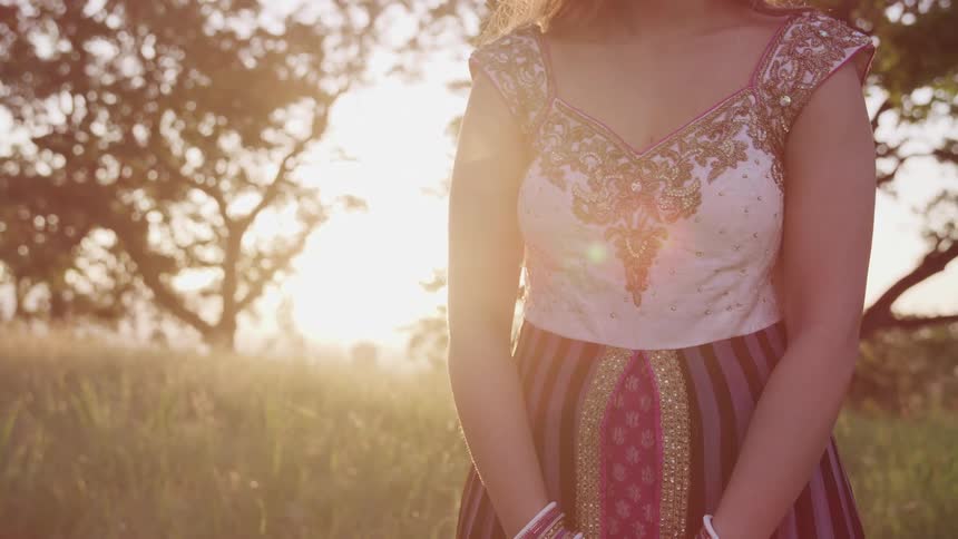A woman is standing outdoors at dusk