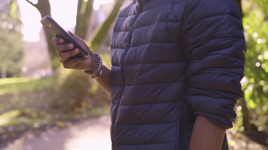 A woman standing outside scrolling on her cell phone