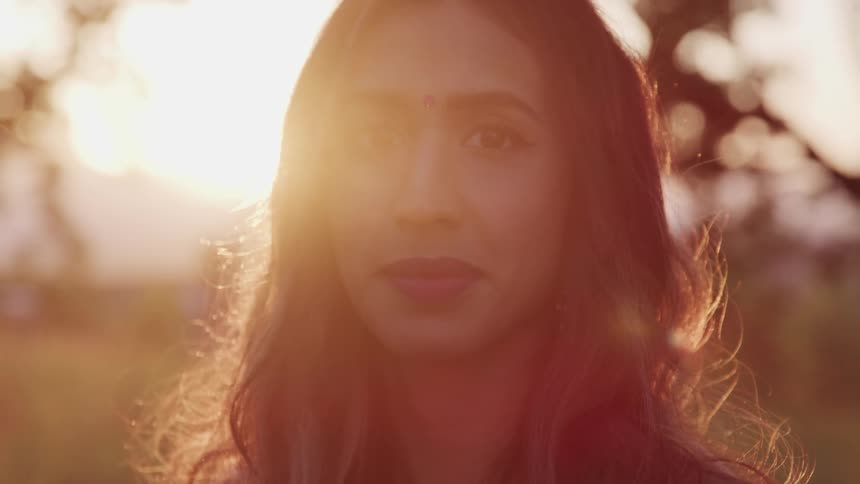 Woman with bindi in forehead looking at the camera at sunset