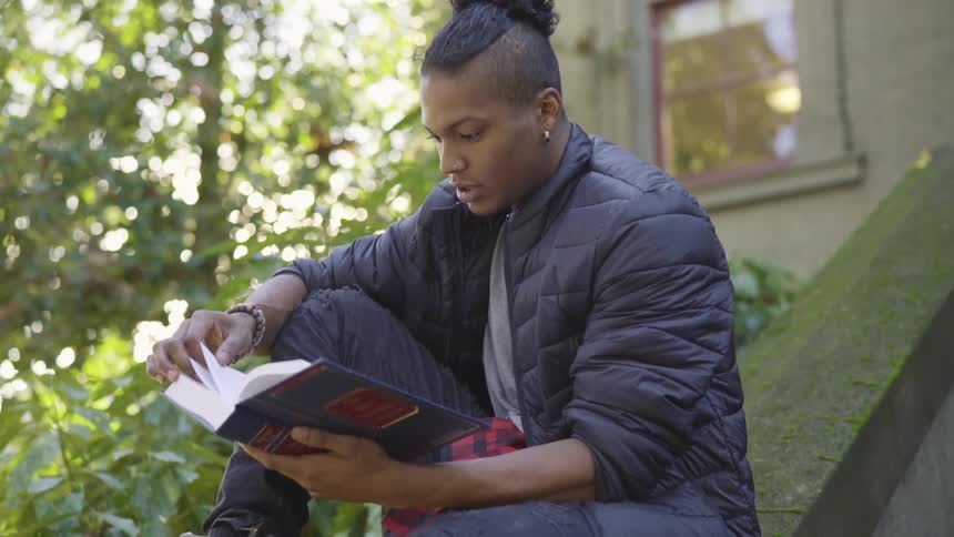 A man is reading a book outdoors in spring