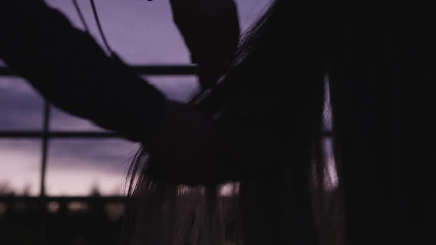 A person brushes the tail of a horse in a farm setting