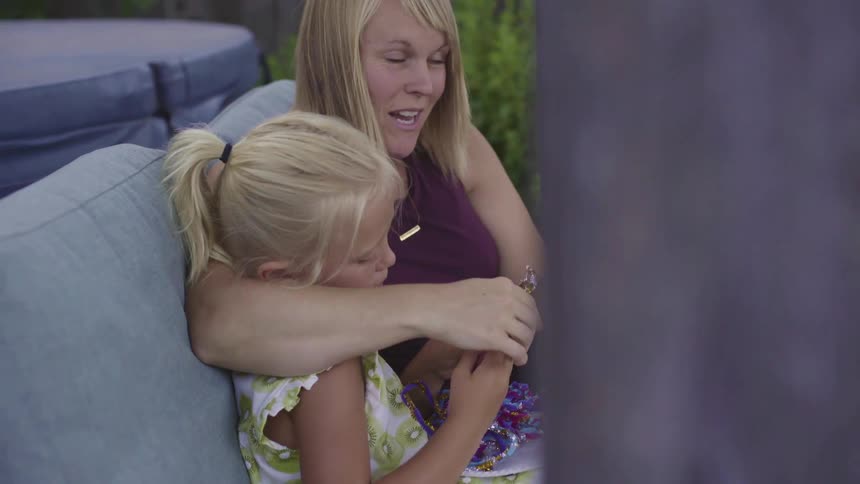 Mother making bracelets with her daughter and son in a couch in the backyard