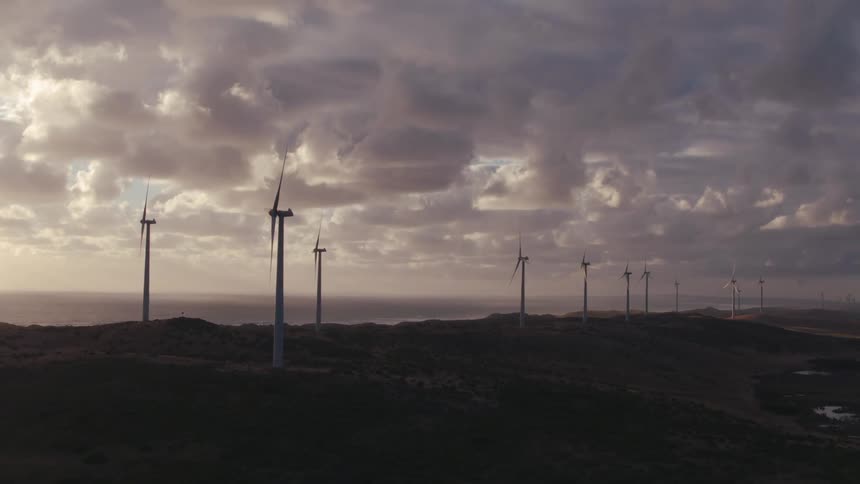 Windmills are shown in a rural area at dusk