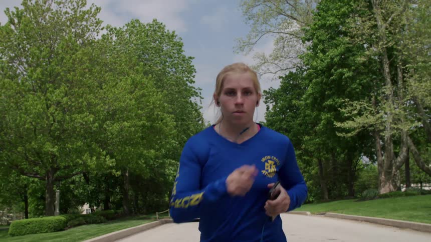 A woman in a blue shirt runs on a street during the day