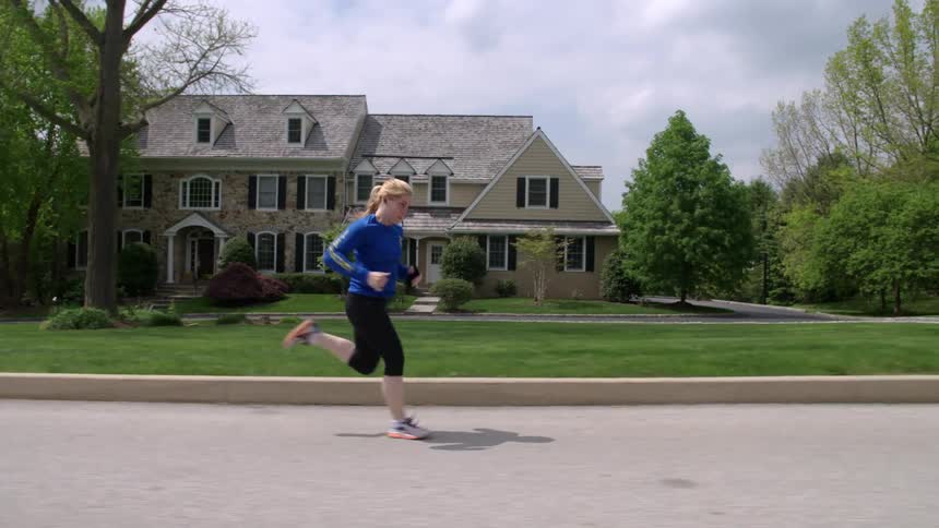 A woman jogs in a residential neighborhood