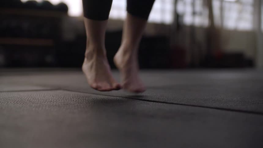 The feet of a person jumping with a jump rope in a gym