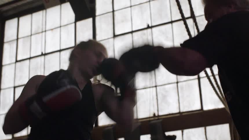 A woman is sparring in a gym