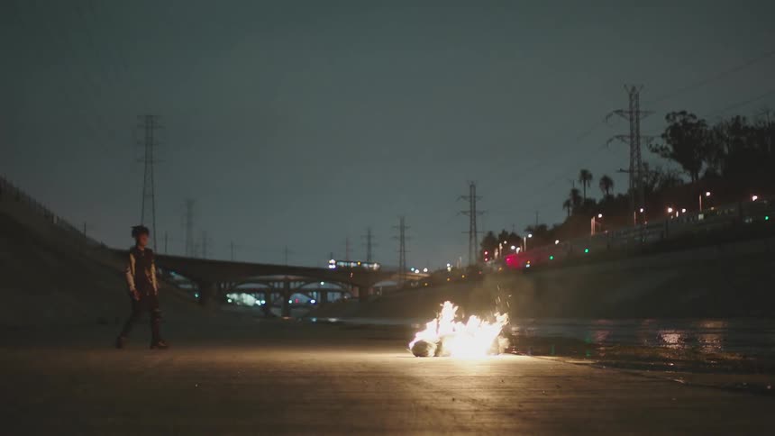A person lights a flare and throws it on a object on the ground to light it in flames