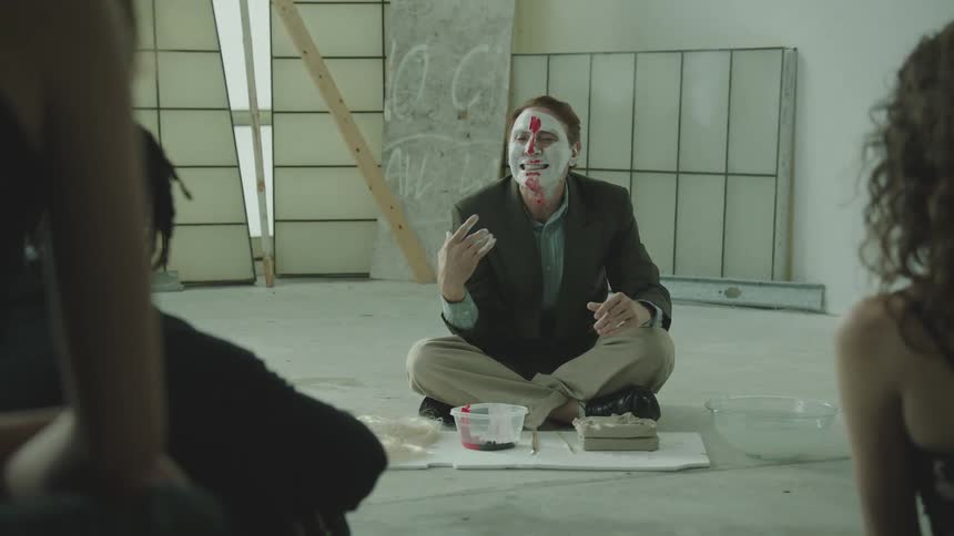 A man is putting paint on his face in front of an audience