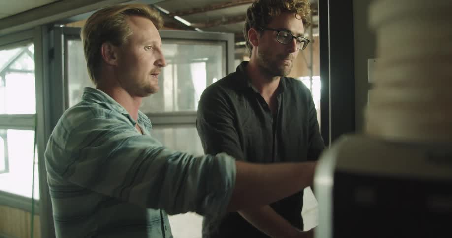 Two men in a factory talk as they look at a computer