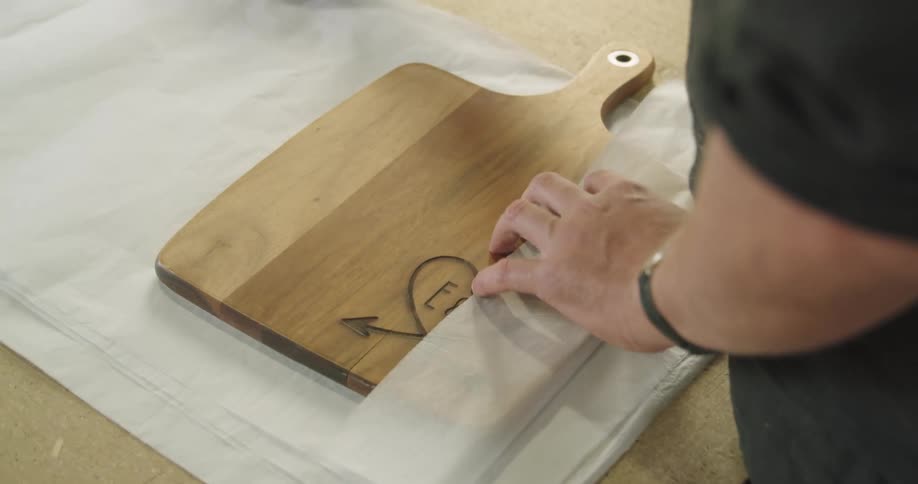 A man wraps kitchen cutting boards with paper over a table