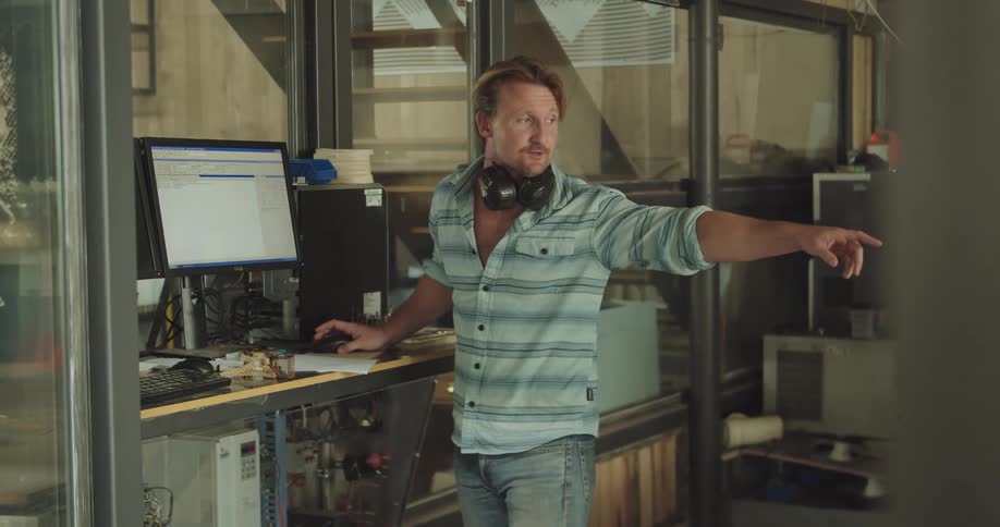 A man looks at a computer screen and turned around to point